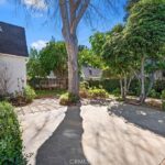 Spacious outdoor area with paved surface, trees, and shrubs.