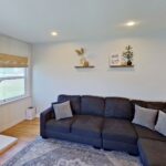 Cozy living room with dark sectional sofa, wall TV, fireplace, and shelves.