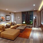 Modern living room with beige sectional, wooden table, wall art, rug, and large windows.